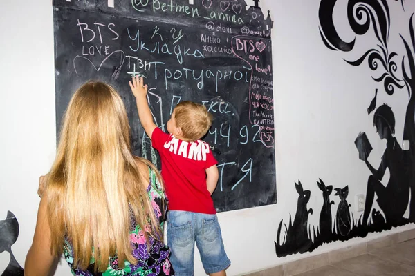 女の子と男の子ドローでチョークで黒黒板にアートカフェ読書室 — ストック写真