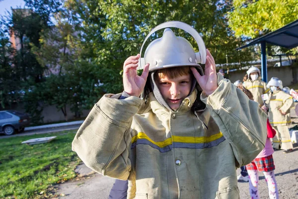 消防士のスーツに身を包んだ少年が市内の消防署で — ストック写真
