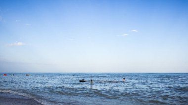 İnsanları denizde ve gökyüzünde bulutlarla yıkıyor.