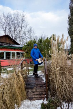 Mavi ceketli bir çocuk dekoratif ahşap bir köprüde duruyor.