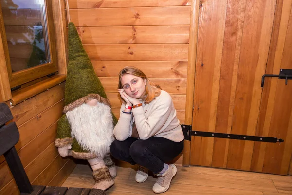 Ein Mädchen Einer Winterblockhütte Sitzt Zusammen Mit Einem Dekorativen Waldzwerg — Stockfoto