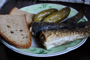 Kızarmış balık, turşu ve bir tabak ekmek.