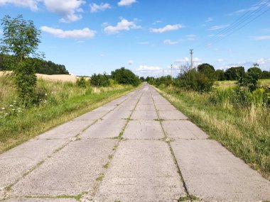 concrete road made of slabs between the fields