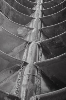 Metal parçaları düzenli aralıklarla metal eksene kaynaklanmış. Siyah ve beyaz soyutlama.