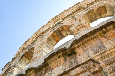 Antik taş bir yapının duvarının alt görüntüsü. Mavi gökyüzünün arka planında kemerler var.