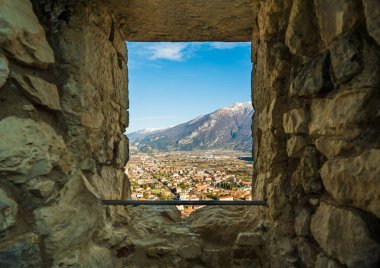 Dağların yakınındaki şehrin manzarası eski taş kalenin penceresinden açılıyor.