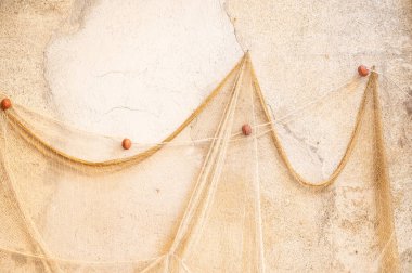 Çamurlu eski bir balıkçı ağı eski bir beton duvarda asılı duruyor.