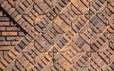 Çok sayıda koyu kırmızı tuğlanın arka planı güzel geometrik desenlerle döşenmiştir.
