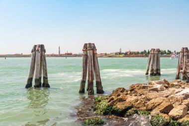 Venedik kıyısında başka bir açı daha var. Kanalın karşı yakasından kayalık bir kıyıdan, tahta kutupların yakınından tekneler için tabelalar.