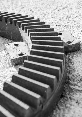 Yuvarlak dişli, destek bacaklı bir detay. Ayak kısmına ve birkaç diş yüzeyine odaklan. Siyah beyaz fotoğraf