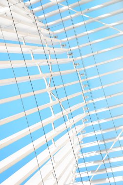 Geometrik soyutlama, bir sürü beyaz ve siyah paralel kıvrımlı çizgiler, geniş ve ince mavi arkaplan üzerinde. Dikey fotoğraf