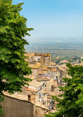 Ufukta iki yeşil ağaç ve sisli tarlalar arasında, İtalyan kasabalarından birinin kiremitli çatısına sahip birkaç taş ev yer alıyor. Dikey fotoğraf
