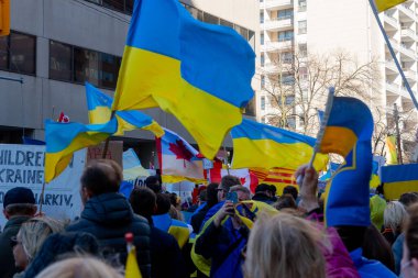 Toronto, Ontario, Kanada 6 Mart 2022: Toronto 'daki Rus konsolosluğu yakınlarında sarı ve mavi Ukrayna bayraklı göstericiler Ukrayna' daki savaş sırasında Ukrayna üzerindeki hava sahasını kapatma talebinde bulundu