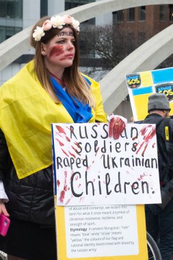 Toronto, ON, Kanada 10 Nisan 2022: Ukraynalıların soykırımını durdurmak için düzenlenen Ukrayna Kanada Kongresi mitinginde Ukrayna şehir merkezindeki Nathan Phillips Meydanı 'nda pankart ve bayraklı protestocular. Putin ve Rus ordusu Uk 'u yok etmek istiyor.