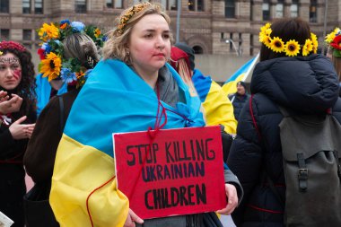 Toronto, ON, Kanada 10 Nisan 2022: Ukraynalıların soykırımını durdurmak için düzenlenen Ukrayna Kanada Kongresi mitinginde Ukrayna şehir merkezindeki Nathan Phillips Meydanı 'nda pankart ve bayraklı protestocular. Putin ve Rus ordusu Uk 'u yok etmek istiyor.