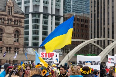 Toronto, ON, Kanada 10 Nisan 2022: Ukraynalıların soykırımını durdurmak için düzenlenen Ukrayna Kanada Kongresi mitinginde Ukrayna şehir merkezindeki Nathan Phillips Meydanı 'nda pankart ve bayraklı protestocular. Putin ve Rus ordusu Uk 'u yok etmek istiyor.