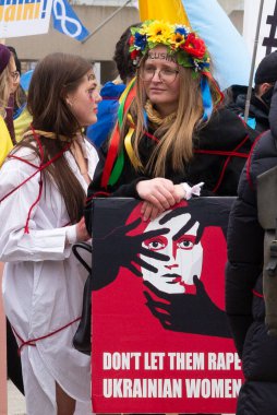 Toronto, ON, Kanada 10 Nisan 2022: Ukraynalıların soykırımını durdurmak için düzenlenen Ukrayna Kanada Kongresi mitinginde Ukrayna şehir merkezindeki Nathan Phillips Meydanı 'nda pankart ve bayraklı protestocular. Putin ve Rus ordusu Uk 'u yok etmek istiyor.