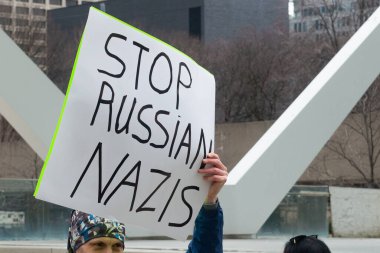 Toronto, ON, Kanada 10 Nisan 2022: Ukraynalıların soykırımını durdurmak için düzenlenen Ukrayna Kanada Kongresi mitinginde Ukrayna şehir merkezindeki Nathan Phillips Meydanı 'nda pankart ve bayraklı protestocular. Putin ve Rus ordusu Uk 'u yok etmek istiyor.