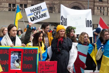 Toronto, ON, Kanada 10 Nisan 2022: Ukraynalıların soykırımını durdurmak için düzenlenen Ukrayna Kanada Kongresi mitinginde Ukrayna şehir merkezindeki Nathan Phillips Meydanı 'nda pankart ve bayraklı protestocular. Putin ve Rus ordusu Uk 'u yok etmek istiyor.