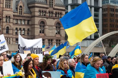 Toronto, ON, Kanada 10 Nisan 2022: Ukraynalıların soykırımını durdurmak için düzenlenen Ukrayna Kanada Kongresi mitinginde Ukrayna şehir merkezindeki Nathan Phillips Meydanı 'nda pankart ve bayraklı protestocular. Putin ve Rus ordusu Uk 'u yok etmek istiyor.