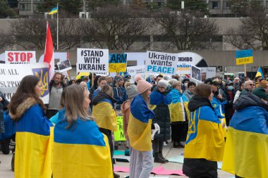 Toronto, ON, Kanada 10 Nisan 2022: Ukraynalıların soykırımını durdurmak için düzenlenen Ukrayna Kanada Kongresi mitinginde Ukrayna şehir merkezindeki Nathan Phillips Meydanı 'nda pankart ve bayraklı protestocular. Putin ve Rus ordusu Uk 'u yok etmek istiyor.
