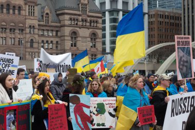 Toronto, ON, Kanada 10 Nisan 2022: Ukraynalıların soykırımını durdurmak için düzenlenen Ukrayna Kanada Kongresi mitinginde Ukrayna şehir merkezindeki Nathan Phillips Meydanı 'nda pankart ve bayraklı protestocular. Putin ve Rus ordusu Uk 'u yok etmek istiyor.
