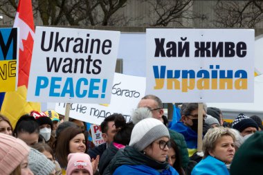 Toronto, ON, Kanada 10 Nisan 2022: Ukraynalıların soykırımını durdurmak için düzenlenen Ukrayna Kanada Kongresi mitinginde Ukrayna şehir merkezindeki Nathan Phillips Meydanı 'nda pankart ve bayraklı protestocular. Putin ve Rus ordusu Uk 'u yok etmek istiyor.