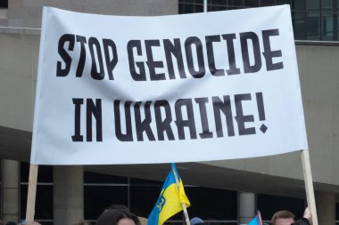 Toronto, ON, Kanada 10 Nisan 2022: Ukraynalıların soykırımını durdurmak için düzenlenen Ukrayna Kanada Kongresi mitinginde Ukrayna şehir merkezindeki Nathan Phillips Meydanı 'nda pankart ve bayraklı protestocular. Putin ve Rus ordusu Uk 'u yok etmek istiyor.
