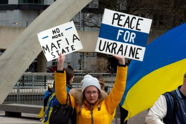 Toronto, ON, Kanada 10 Nisan 2022: Ukraynalıların soykırımını durdurmak için düzenlenen Ukrayna Kanada Kongresi mitinginde Ukrayna şehir merkezindeki Nathan Phillips Meydanı 'nda pankart ve bayraklı protestocular. Putin ve Rus ordusu Uk 'u yok etmek istiyor.