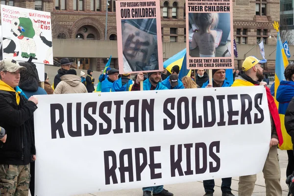 Toronto, ON, Kanada 10 Nisan 2022: Ukraynalıların soykırımını durdurmak için düzenlenen Ukrayna Kanada Kongresi mitinginde Ukrayna şehir merkezindeki Nathan Phillips Meydanı 'nda pankart ve bayraklı protestocular. Putin ve Rus ordusu Uk 'u yok etmek istiyor.