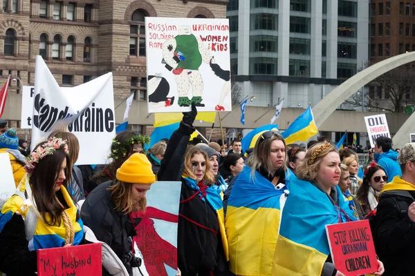 Toronto, ON, Kanada 10 Nisan 2022: Ukraynalıların soykırımını durdurmak için düzenlenen Ukrayna Kanada Kongresi mitinginde Ukrayna şehir merkezindeki Nathan Phillips Meydanı 'nda pankart ve bayraklı protestocular. Putin ve Rus ordusu Uk 'u yok etmek istiyor.