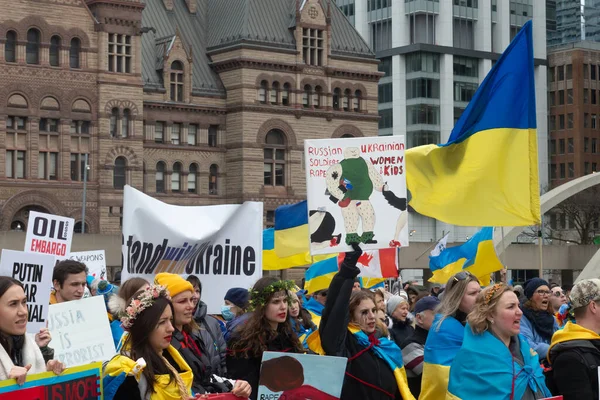 Toronto, ON, Kanada 10 Nisan 2022: Ukraynalıların soykırımını durdurmak için düzenlenen Ukrayna Kanada Kongresi mitinginde Ukrayna şehir merkezindeki Nathan Phillips Meydanı 'nda pankart ve bayraklı protestocular. Putin ve Rus ordusu Uk 'u yok etmek istiyor.
