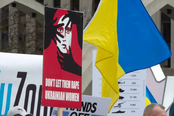 Toronto, ON, Kanada 10 Nisan 2022: Ukraynalıların soykırımını durdurmak için düzenlenen Ukrayna Kanada Kongresi mitinginde Ukrayna şehir merkezindeki Nathan Phillips Meydanı 'nda pankart ve bayraklı protestocular. Putin ve Rus ordusu Uk 'u yok etmek istiyor.