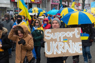 Toronto, ON, Kanada 10 Nisan 2022: Ukraynalıların soykırımını durdurmak amacıyla düzenlenen miting sırasında Ukrayna şehir merkezinde pankartlı ve Ukrayna bayraklı protestocular.