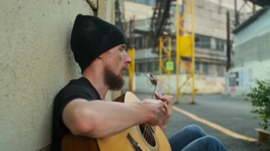 Sokakta çitlere yaslanan evsiz bir adam gitar çalarak para kazanıyor. Yıkılmış bir insan, yoksulluk, sefalet, işten çıkarılma, kovulma, kovulma. Sosyal sorunlar, işsizlik kavramı