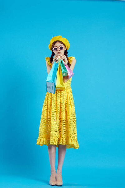 cheerful woman yellow dress shopping fun blue background