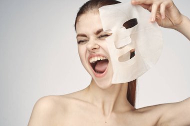 Çıplak omuzlu ve yüz maskeli cilt bakım ürünleri olan bir kadın.