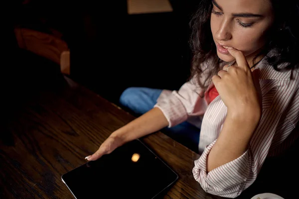 Mujer en un café en una mesa frente a un dispositivo portátil de comunicación — Foto de Stock