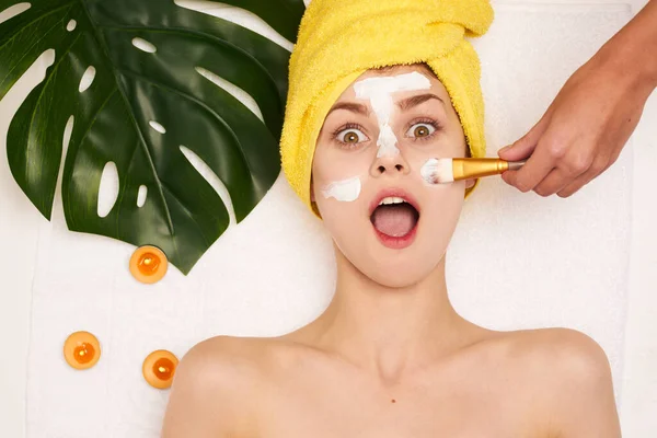Aantrekkelijke vrouw gezicht masker huid reinigen palm blad licht achtergrond — Stockfoto