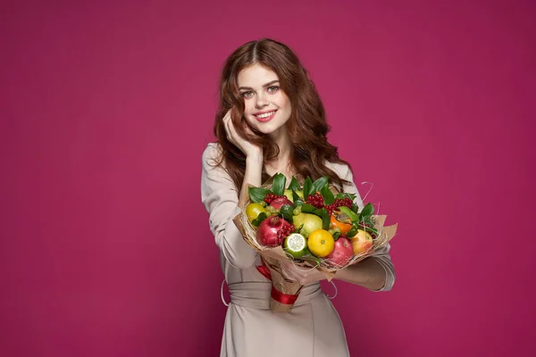 Bella donna trucco luminoso aspetto attraente un mazzo di frutta sfondo rosa — Foto Stock