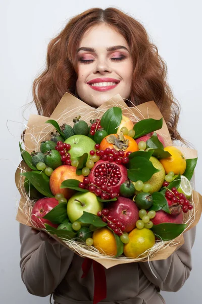 Donna allegra trucco luminoso aspetto attraente un mazzo di frutta sfondo chiaro — Foto Stock