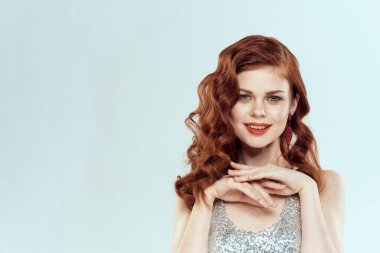 Glamor pozu veren gümüş elbiseli, şık saç stili dekorasyonlu bir kadın.