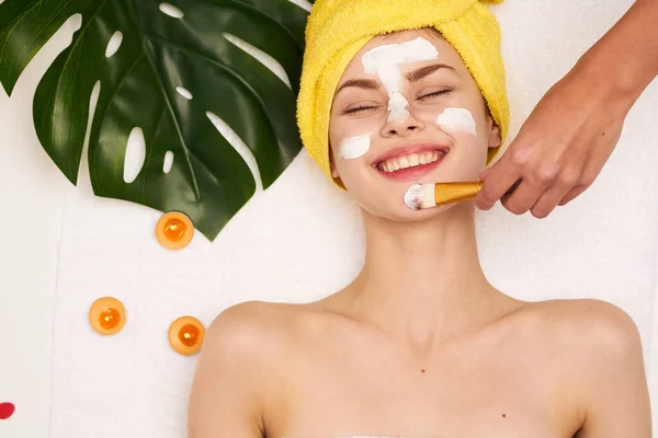 Mooie vrouw gezicht masker huid reinigen palm blad licht achtergrond — Stockfoto