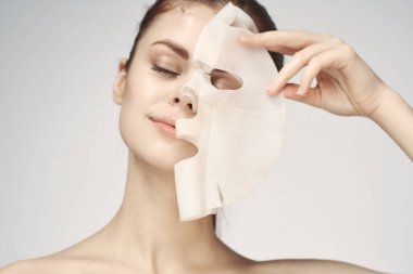 Çıplak omuzlu ve yüz maskeli cilt bakım ürünleri olan bir kadın.