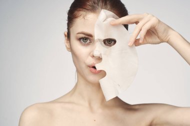Çıplak omuzlu ve yüz maskeli cilt bakım ürünleri olan bir kadın.