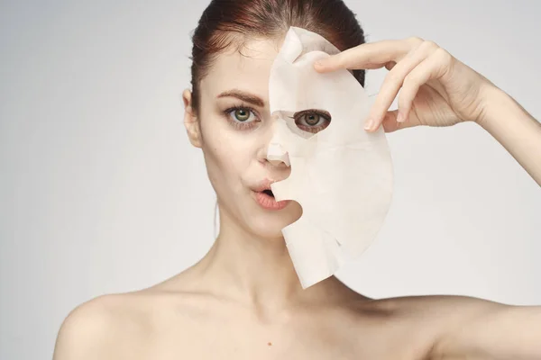 Çıplak omuzlu ve yüz maskeli cilt bakım ürünleri olan bir kadın. — Stok fotoğraf