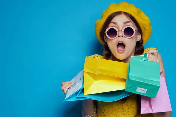 Glad kvinna bär solglasögon poserar shopping mode blå bakgrund — Stockfoto