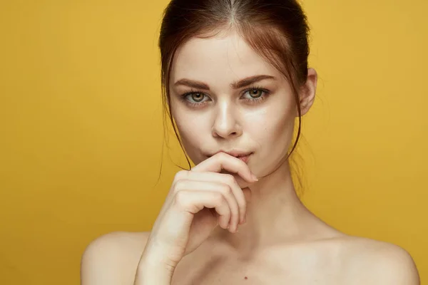 Vacker kvinna nakna axlar och poserar klar hud gul bakgrund — Stockfoto