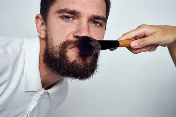 Vousatý muž make-up kosmetika péče o pleť světlé pozadí — Stock fotografie