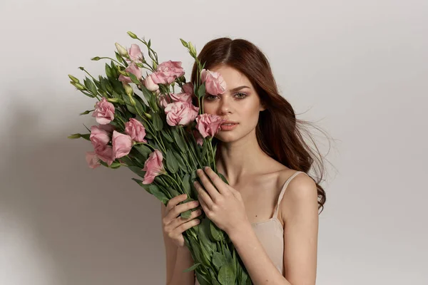 Attrayant femme en robe posant fleurs maquillage fond clair — Photo